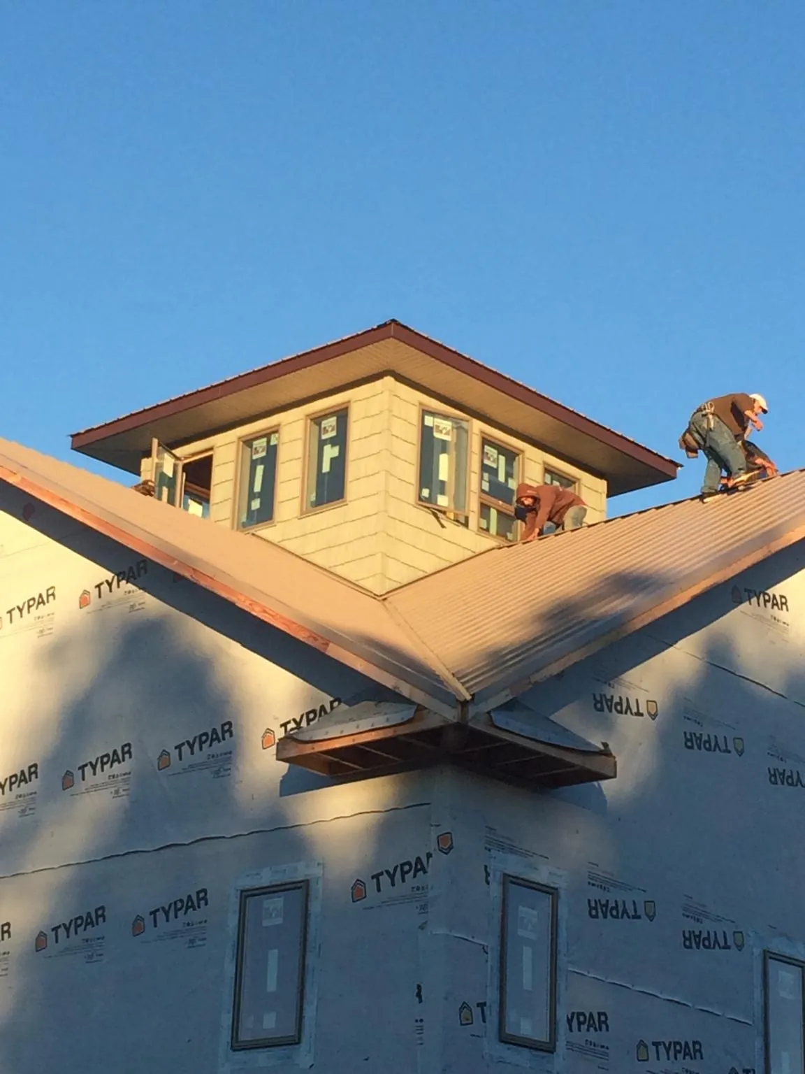Roofers working around a rooftop cupola on a new metal roof at sunset — Roof Waterproofing in Kinston by Roofing Brothers